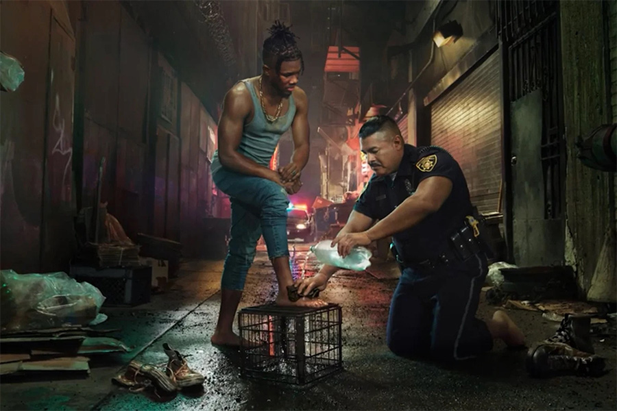 Image of a police officer washing the feet of another man in an alley.